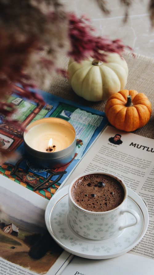 Free Warm autumn scene with coffee, candle, pumpkins, and newspapers inviting relaxation. Stock Photo