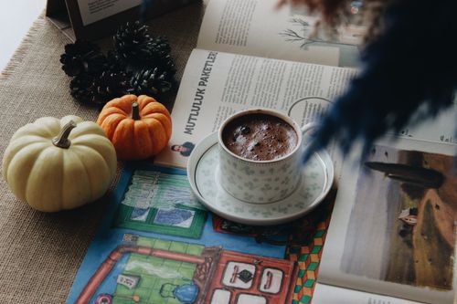 Free A warm, inviting scene with a coffee cup amidst pumpkins, a newspaper, and autumn decor. Stock Photo