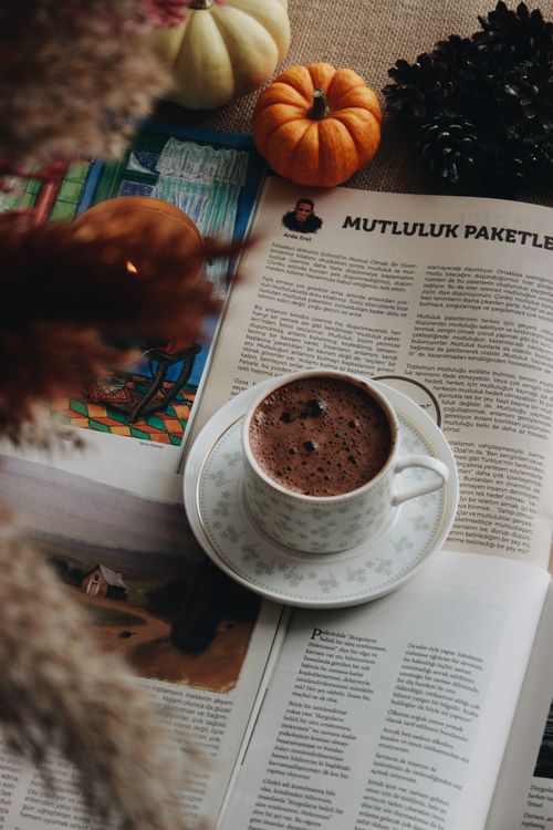 Free Warm cup of hot chocolate on a magazine with pumpkins and fall decor, creating a cozy autumn vibe. Stock Photo