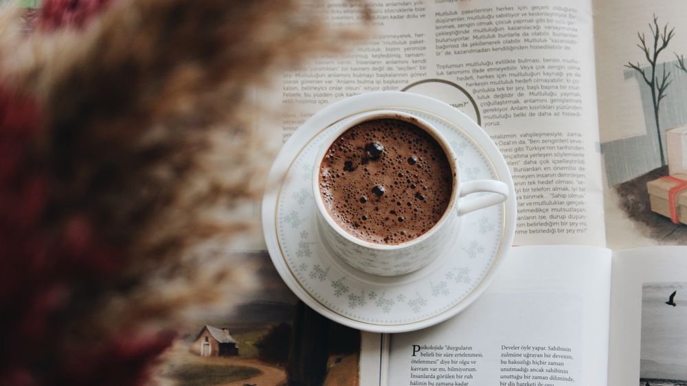 Taza de café humeante sobre un libro abierto
