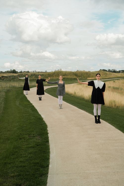 Free Four women in varied outfits stand arms outstretched on a scenic pathway, practicing social distance. Stock Photo