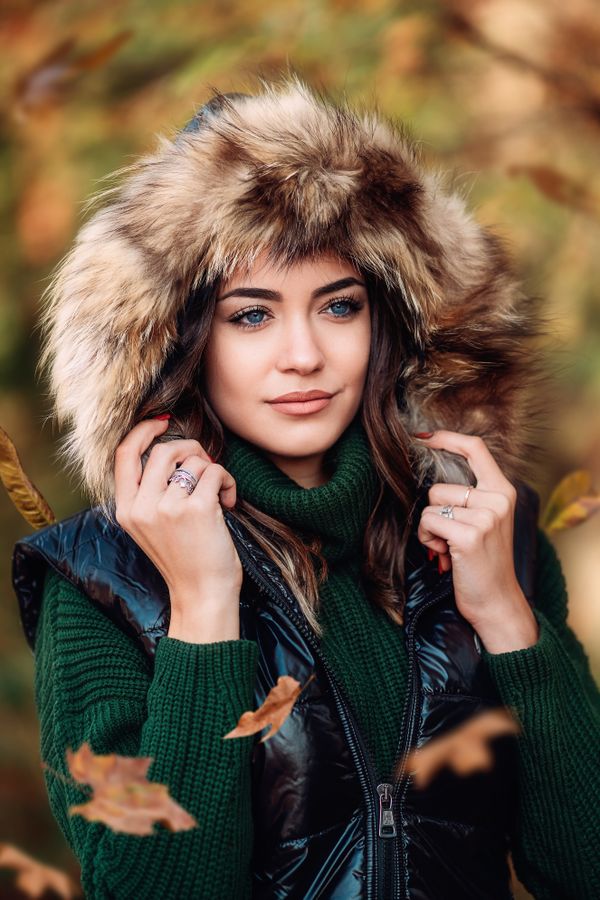 Woman in green turtleneck with fur-trimmed vest in autumn