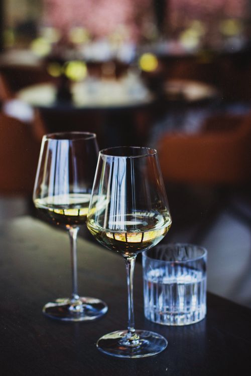 Free Two glasses of white wine on a table in a cozy restaurant setting, perfect for dining ambience. Stock Photo