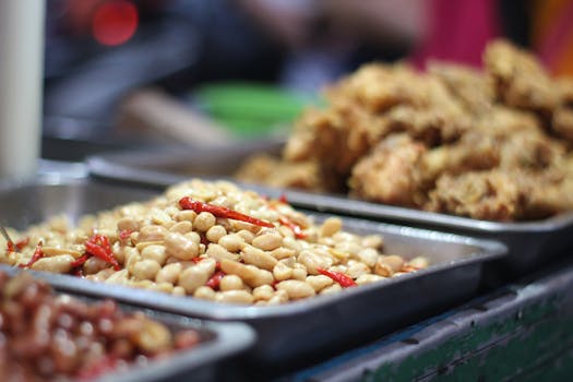 Close-up of a spicy peanut mix and fried snacks on a stainless steel tray, ideal for street food themes.