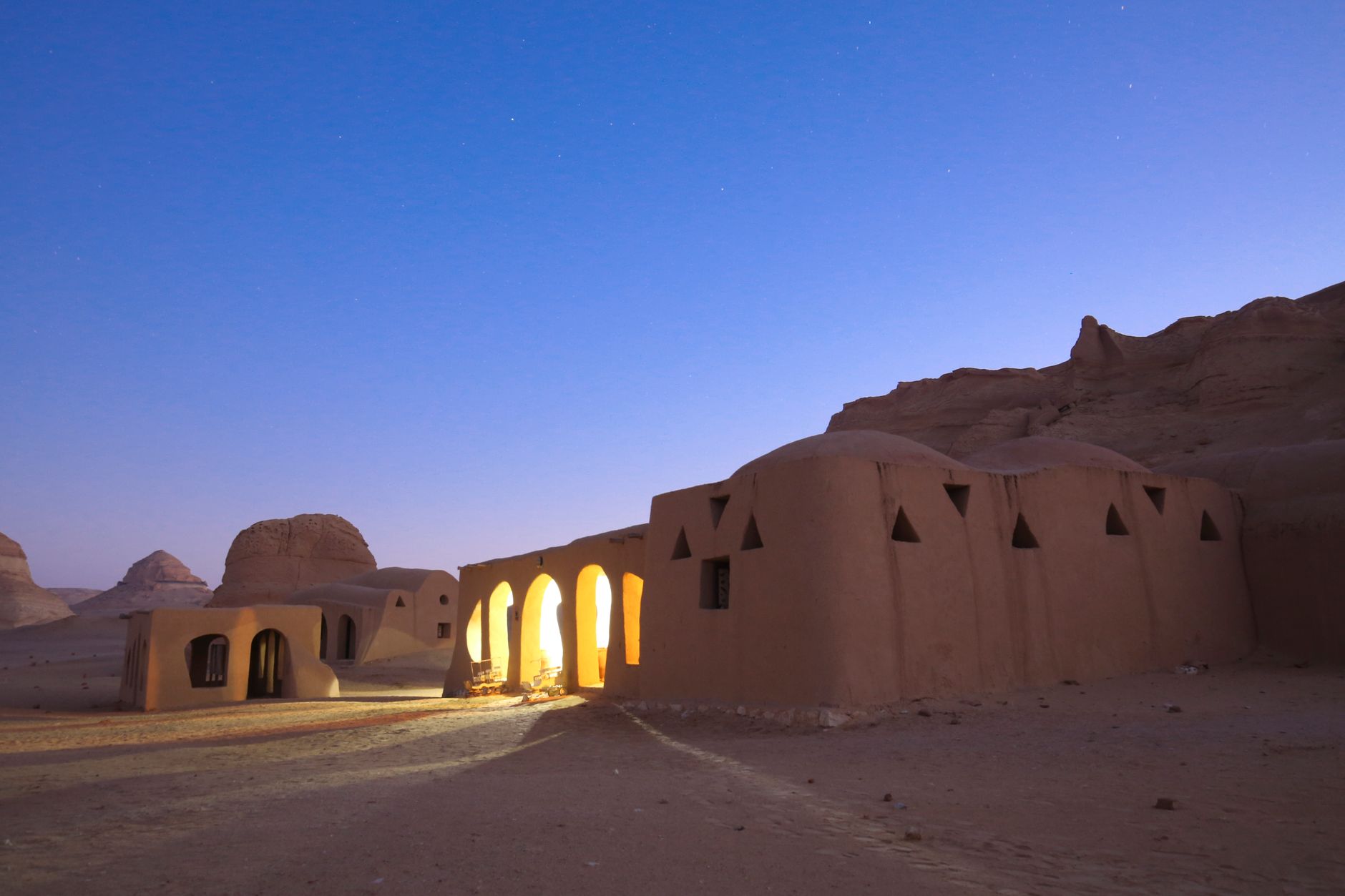 Adobe-style desert homes illuminated at twilight, showcasing a serene architectural landscape.