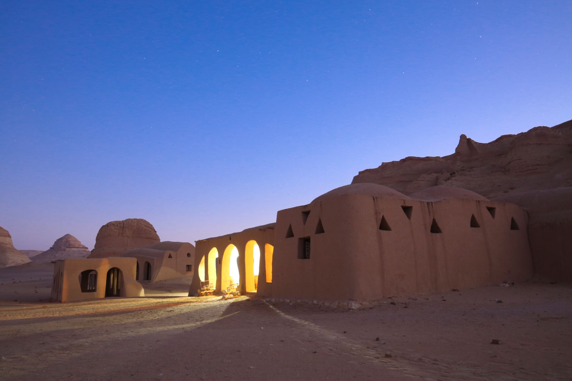 Adobe-style desert homes illuminated at twilight, showcasing a serene architectural landscape.