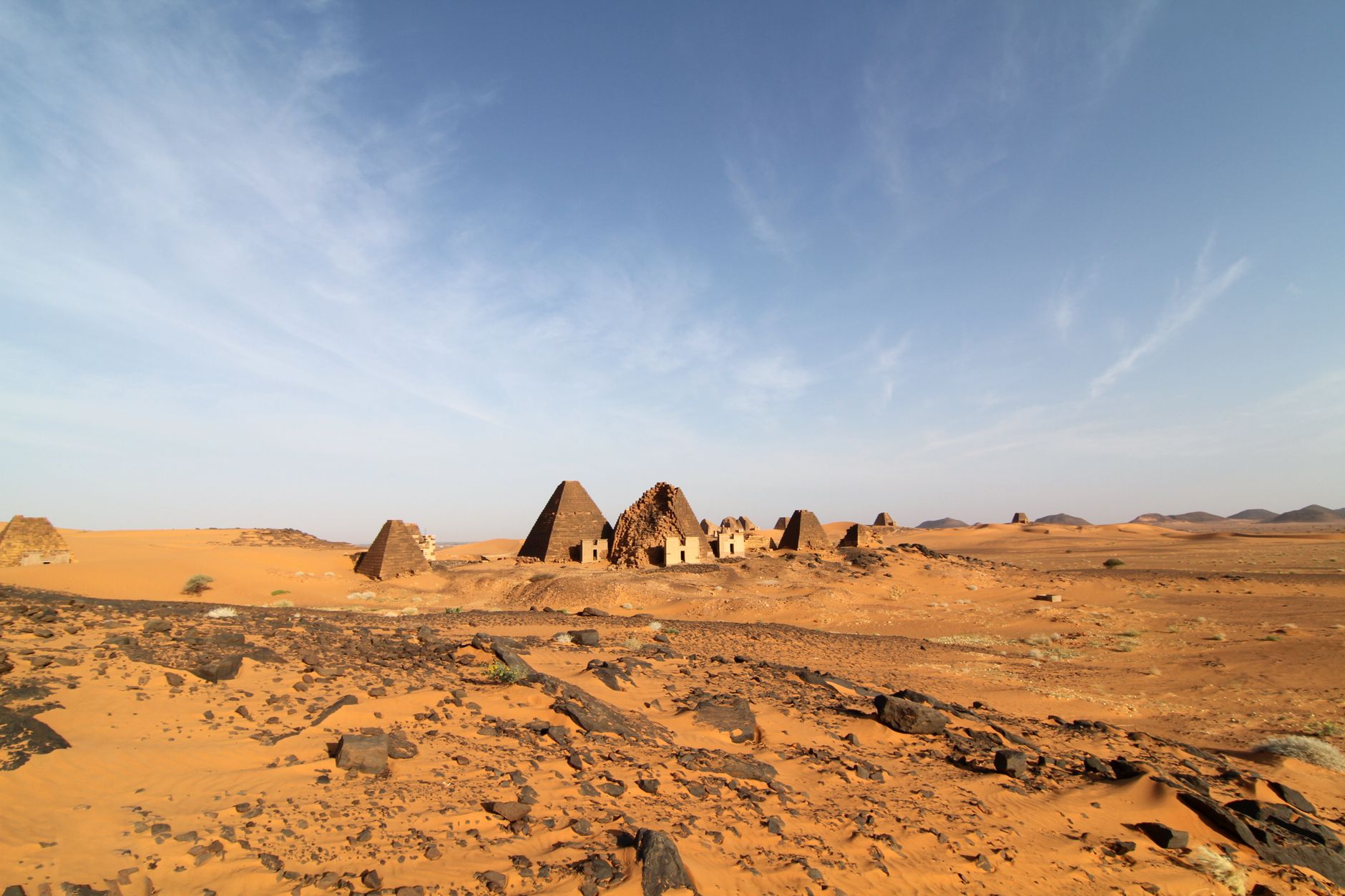 Ancient Meroe pyramids stand in the arid desert under a clear sky, showcasing Sudan's rich history.
