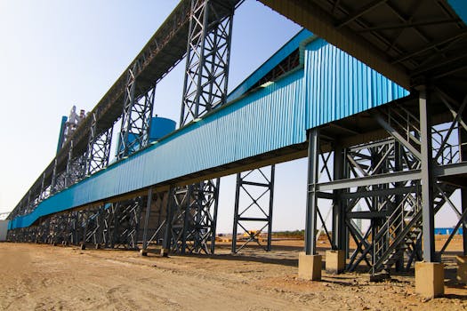 Modern industrial building with blue metal cladding and steel framework in a construction site.