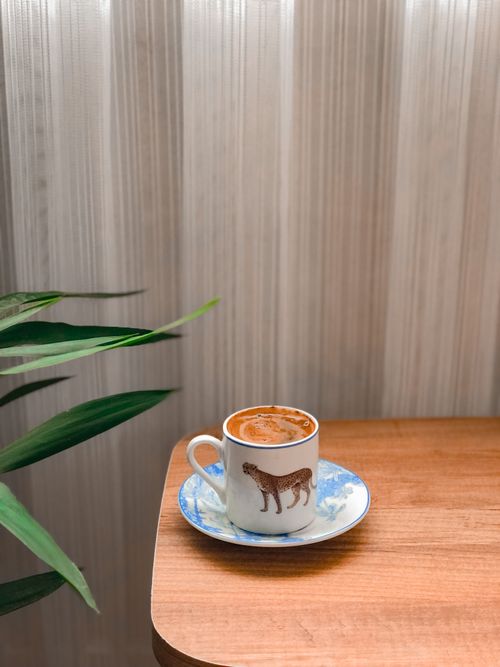 Free Simple yet artistic photo of a coffee cup on a wooden table, perfect for relaxing moments. Stock Photo