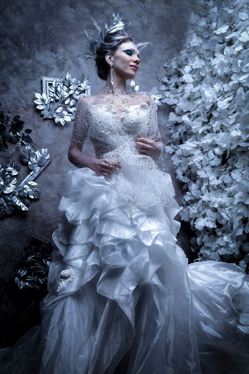 Free Stunning fashion portrait of a woman in an elegant white gown and headdress, posing indoors. Stock Photo