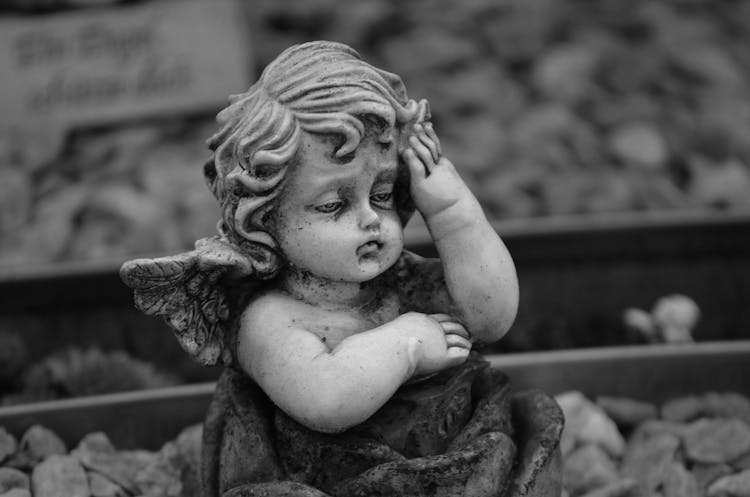 Grayscale Photography Of A Baby Angel Sculpture 