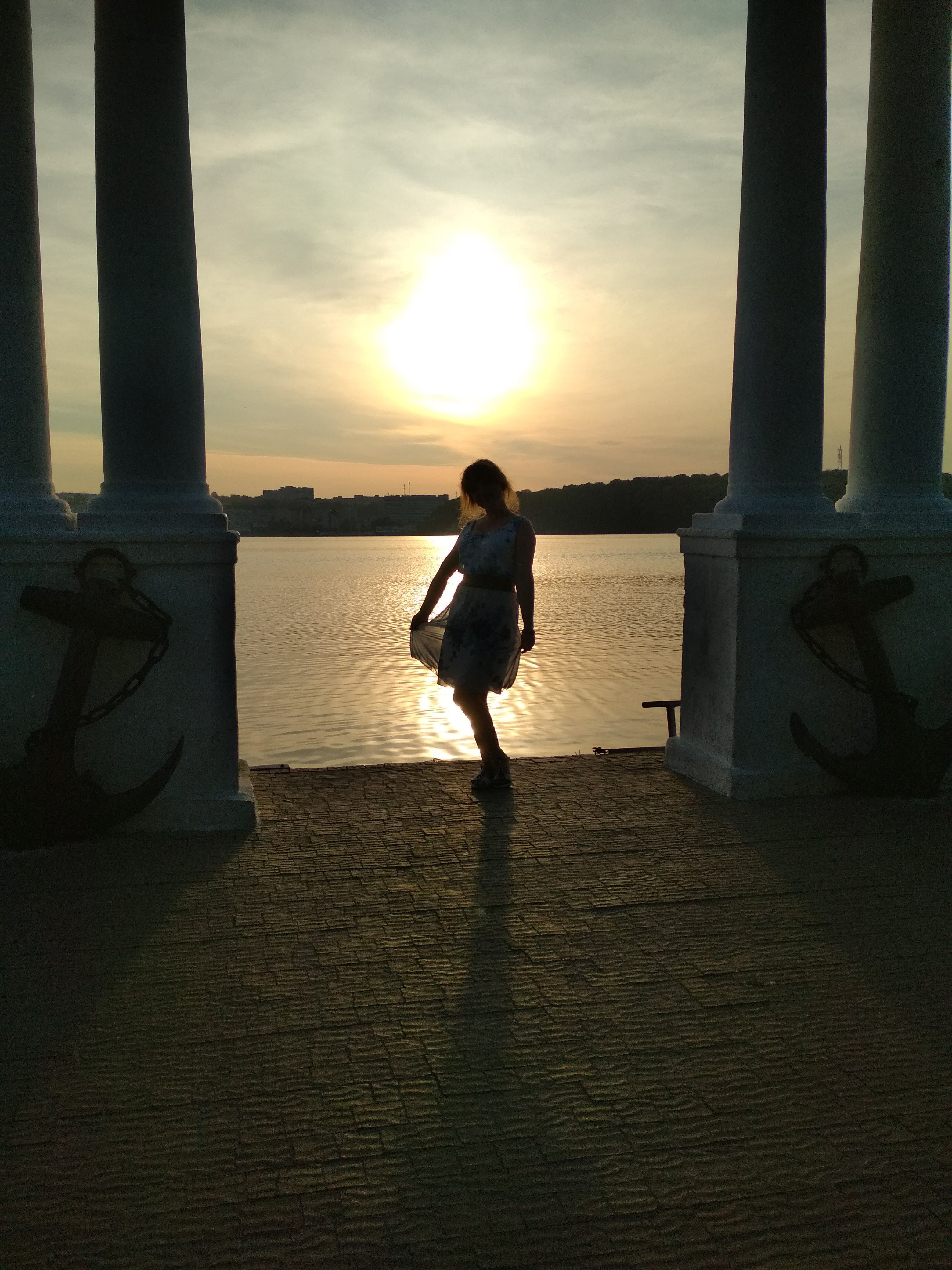 Silhouette of a Woman Standing on a Pier at Sunset · Free Stock Photo
