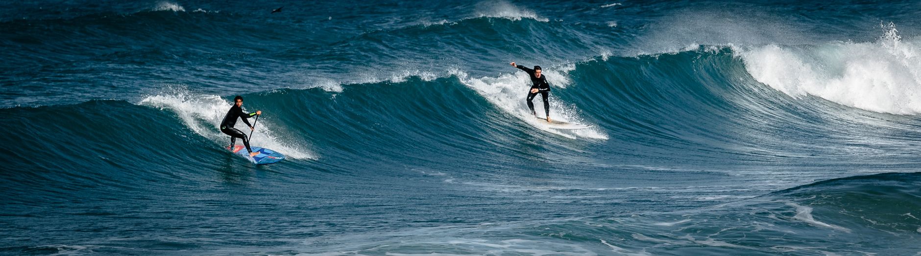 Two surfers ride the waves at Tel Aviv beach, showcasing excitement and skill.