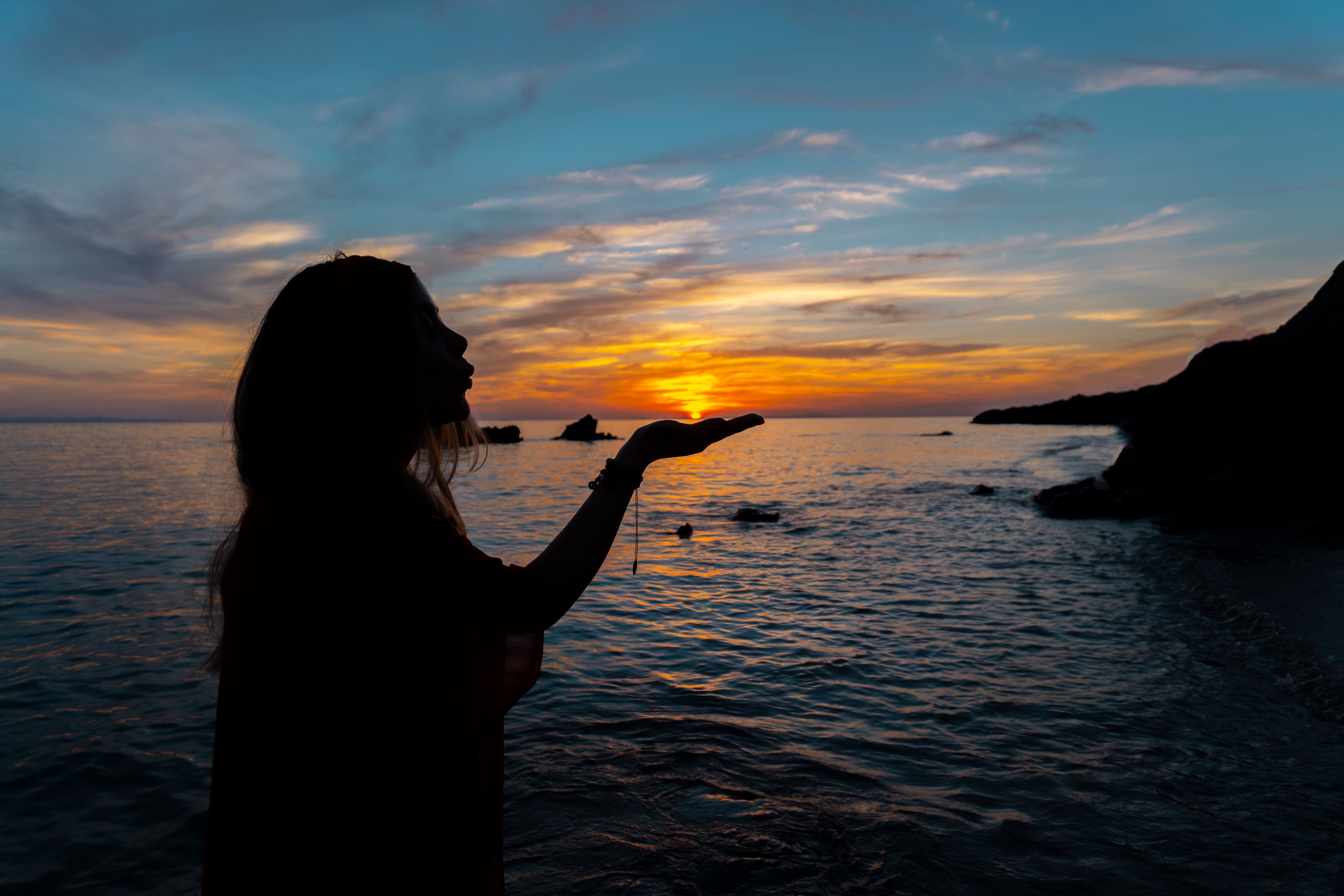 Silhouette of Woman Standing on Seashore during Sunset · Free Stock Photo