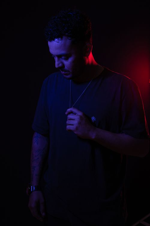 Free Close-up portrait of a man in low light with red and blue hues, creating a moody atmosphere. Stock Photo