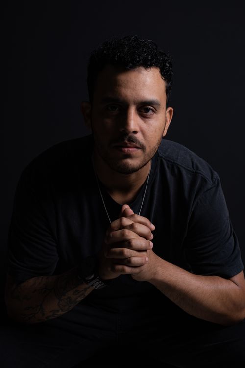 Free Expressive portrait of a man with hands clasped in thoughtful pose, set against a dark background. Stock Photo