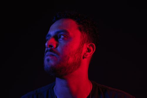 Free A striking portrait of a man under red and blue lighting, showcasing mood and expression. Stock Photo