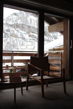 A warm interior view of a balcony overlooking snowy mountains, perfect for winter relaxation.