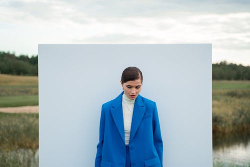 Woman in White Shirt and Blue Blazer Standing Beside White Wall