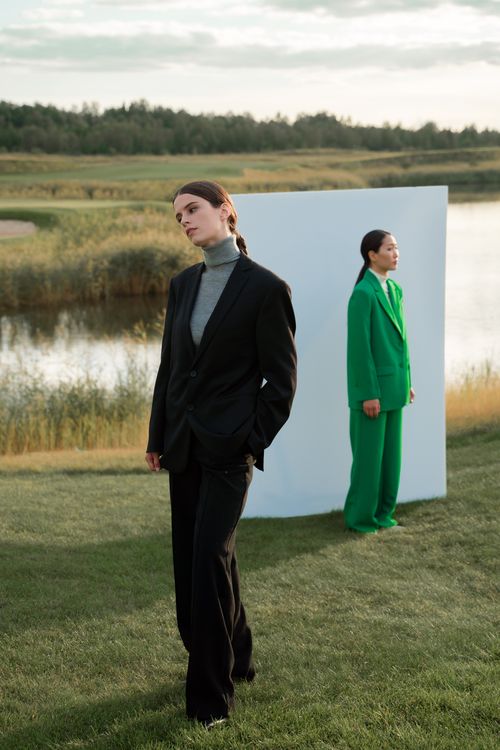 Free Two individuals in stylish suits posing by a serene lakeside backdrop. Stock Photo