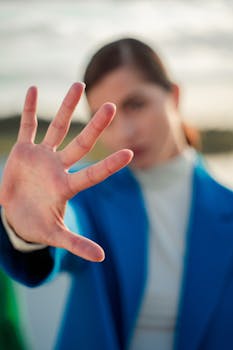 Blurred portrait of a stylish woman posing with hand gesturing stop, outdoors.