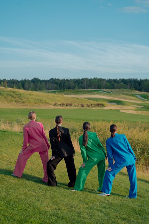 Free Four women in colorful suits pose elegantly in a vibrant meadow setting. Stock Photo