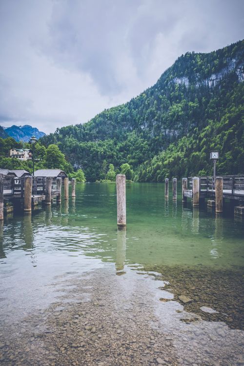 Free Tranquil lake surrounded by lush mountains and a rustic wooden pier. Perfect for nature and travel inspiration. Stock Photo