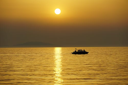 Free People on a Boat at Sea During Sunset Stock Photo