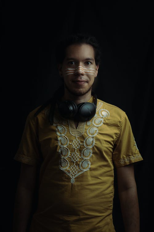 A Man in Yellow Shirt Wearing Black Headphones Looking at the Camera