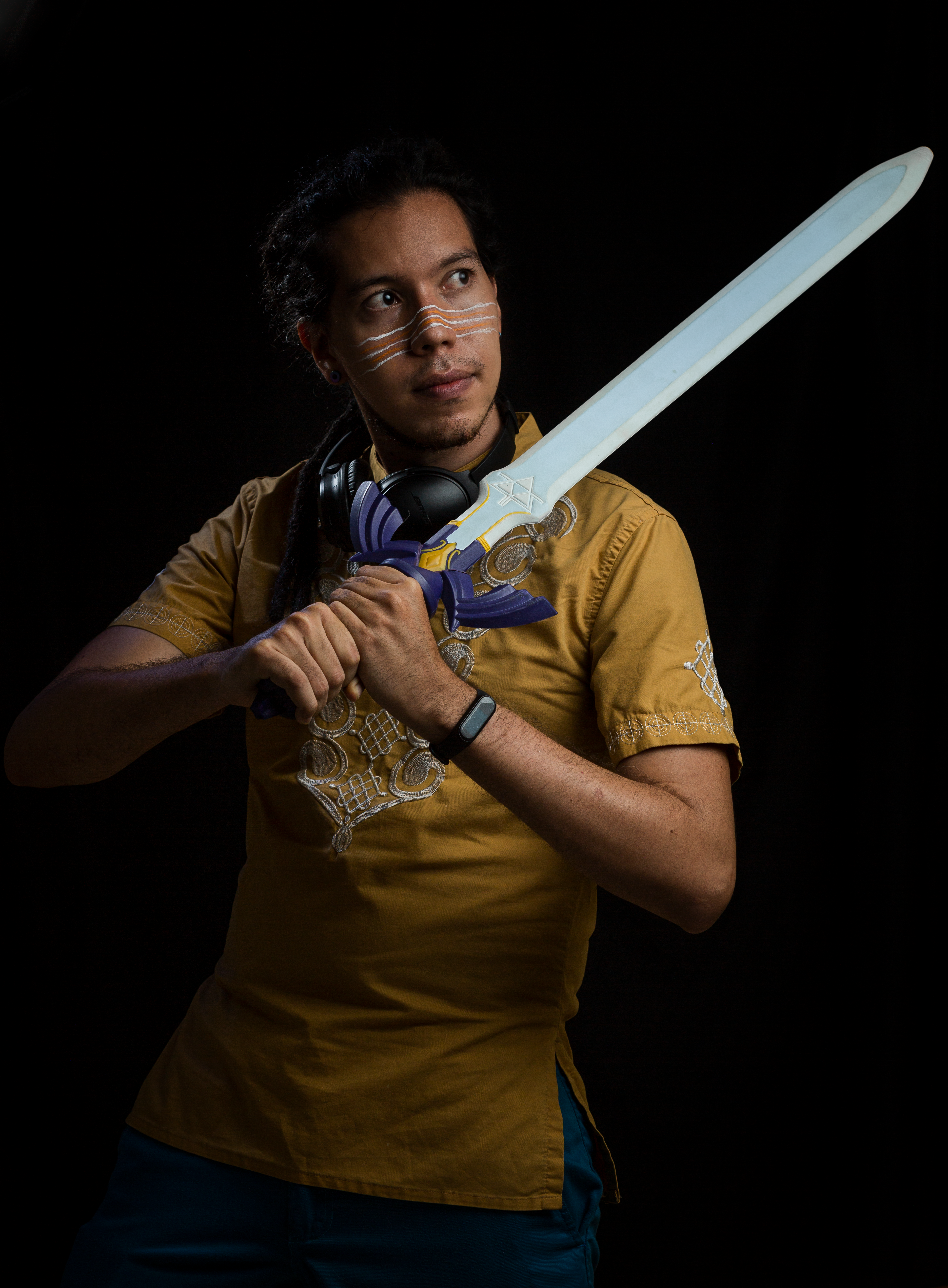 Creative portrait of a man holding a decorative sword against a dark background.