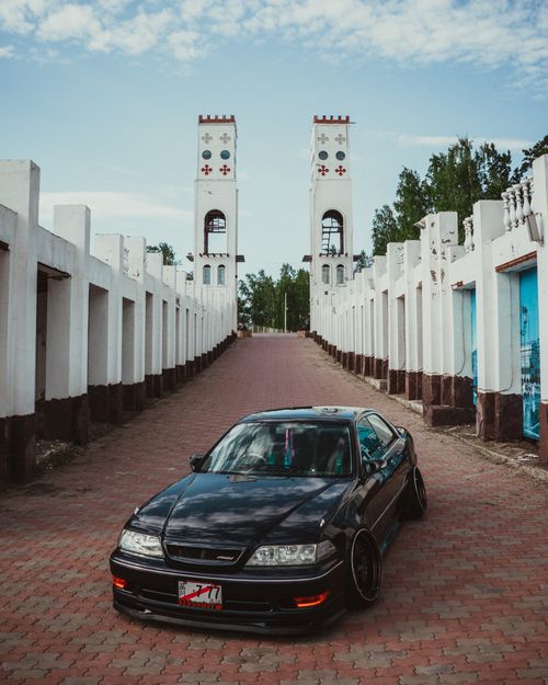 Free Black car parked in front of a historical landmark with unique architectural elements under a clear sky. Stock Photo
