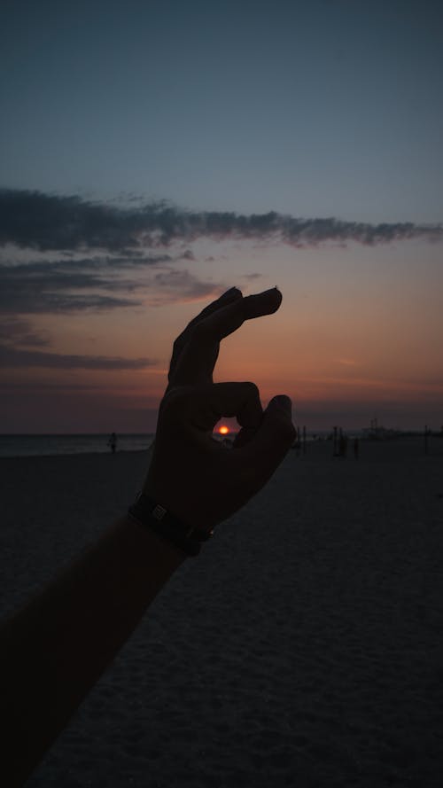 Silhouette of a Mans Hand on the Beach at Sunset 