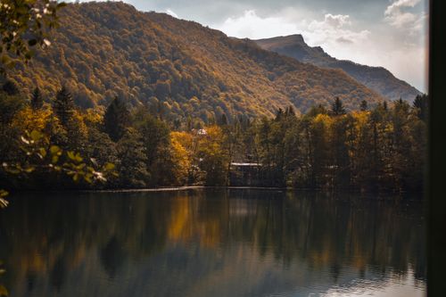 Free Peaceful autumn scene of a tranquil lake reflecting the forest and mountains. Stock Photo