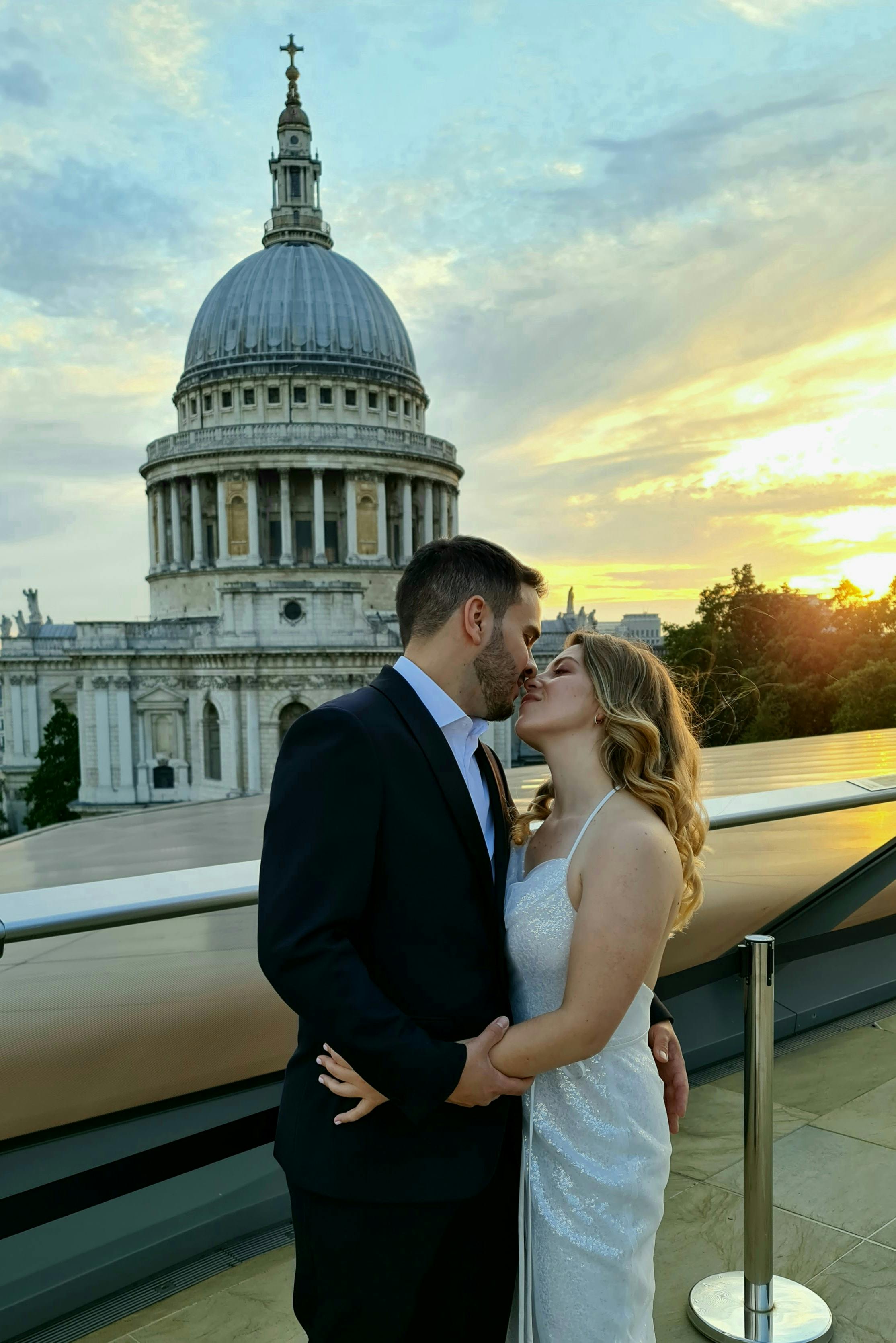 A loving couple shares a kiss with St. Paul's Cathedral at sunset in London.