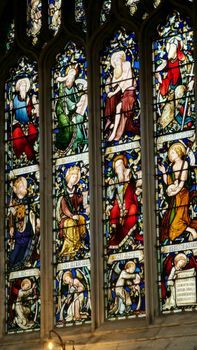 Detailed stained glass window depicting biblical scenes in an English church interior.