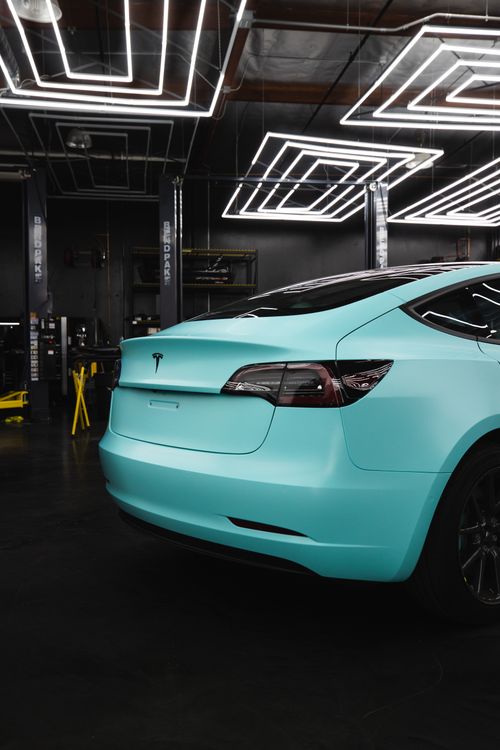 Free A modern teal electric car positioned in a high-end garage with unique ceiling lights, showcasing its luxury and style. Stock Photo