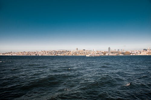 Photo of a Blue Ocean Near a City with Buildings