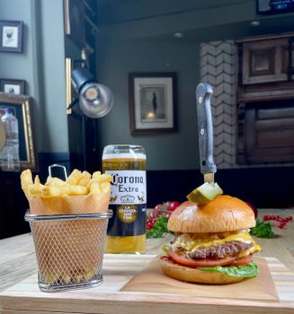 A delicious cheeseburger with fries and beer in a cozy indoor setting. Perfect for food lovers.
