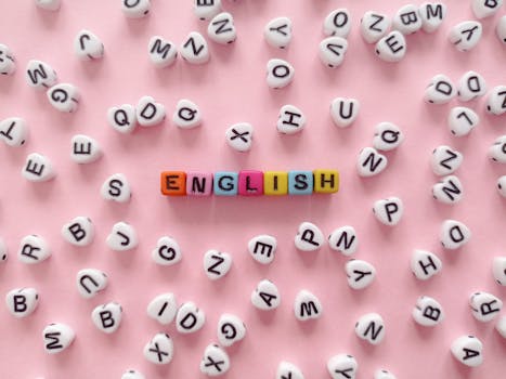 Scattered letter beads form the word 'English' on a pink background, symbolizing language learning.