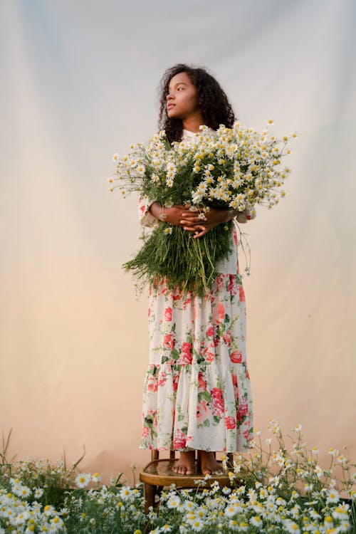 Young Woman Holding Flowers and Standing on Stool