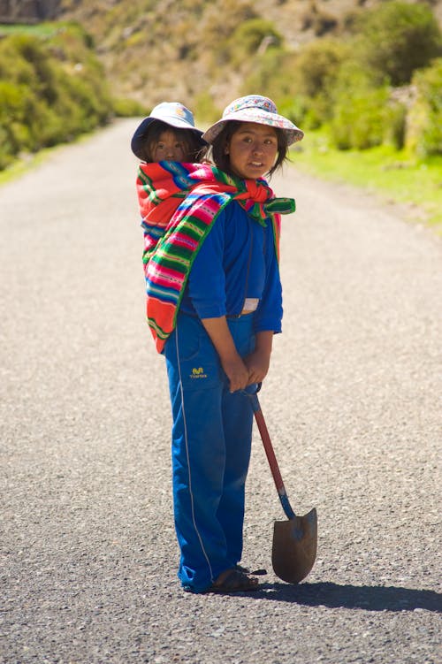 Woman in Blue Clothing Carrying a Baby on her Back