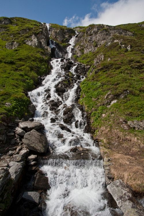 Free Refreshing waterfall cascading down lush green mountain rocks, capturing the essence of untouched nature. Stock Photo