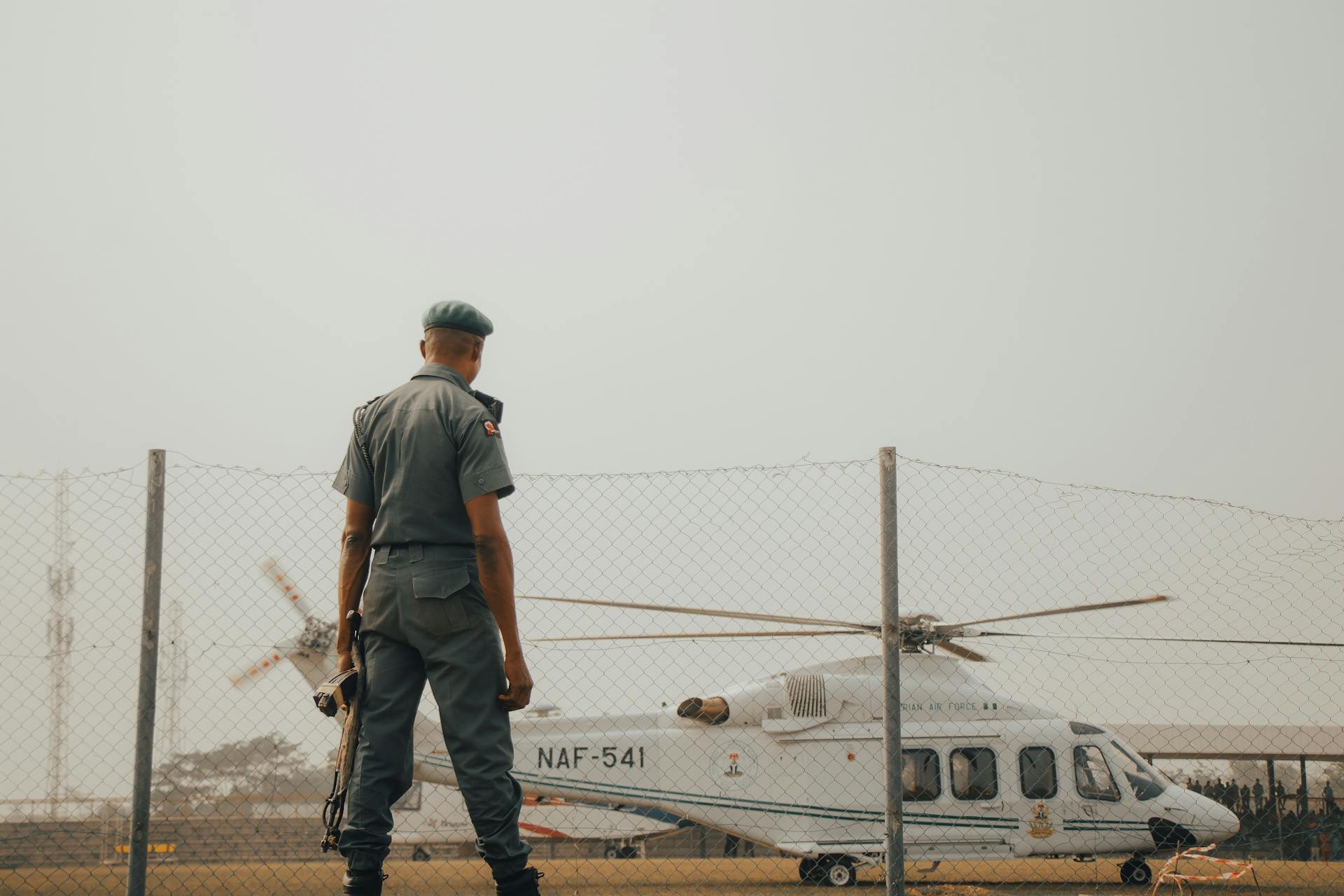 A military officer stands watch by an NAF helicopter fenced area in Nigeria.