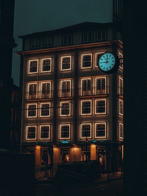 Free A beautifully illuminated building showcases an exterior clock in Porto at night. Stock Photo