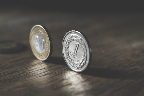 Photo of Two Gold-colored and Silver-colored Coins Standing on Floor