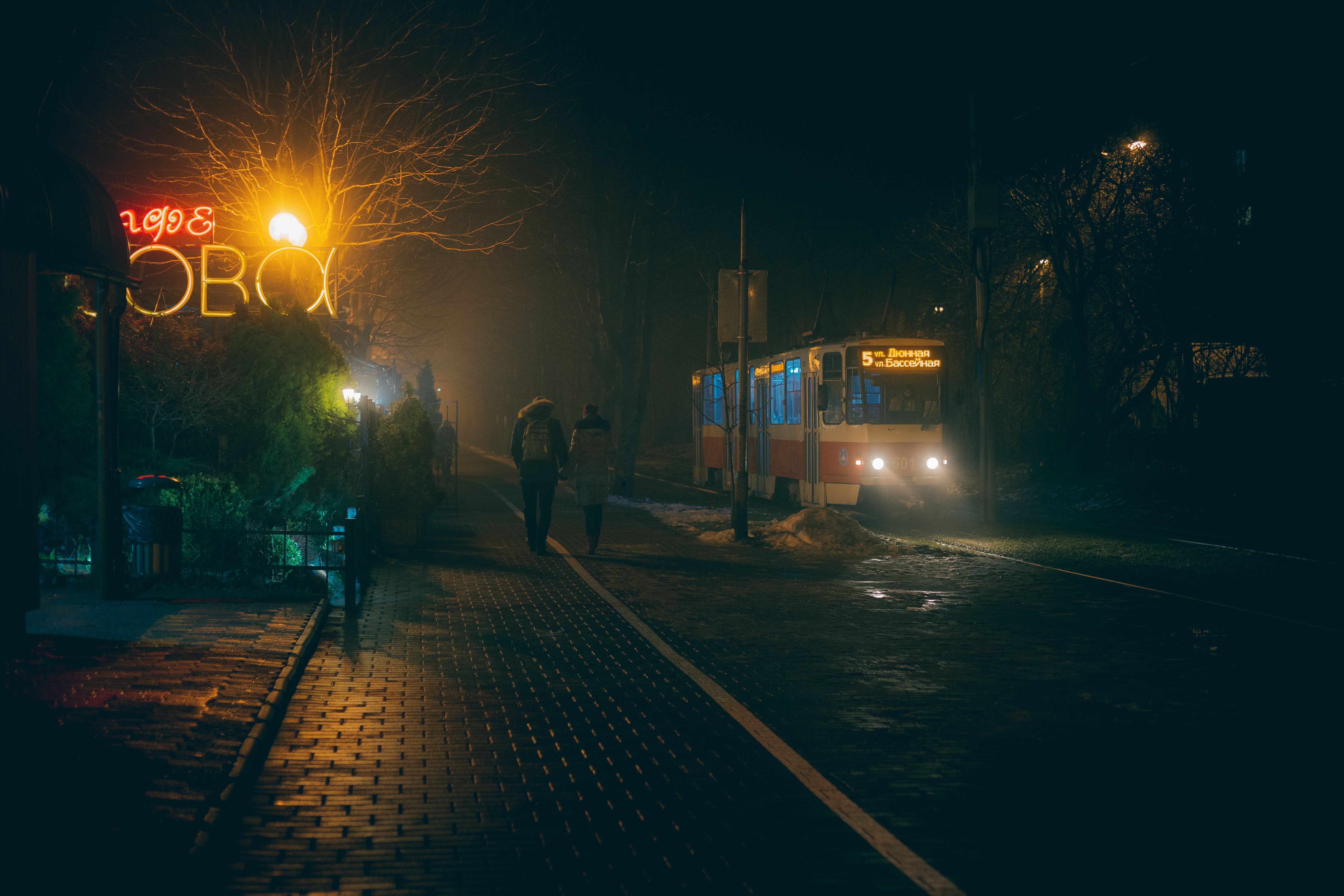 A quiet street in Lisbon at night with a couple walking under warm streetlights