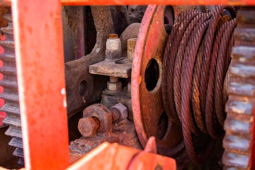 Detailed view of rusty machinery showcasing gears and coiled rope.