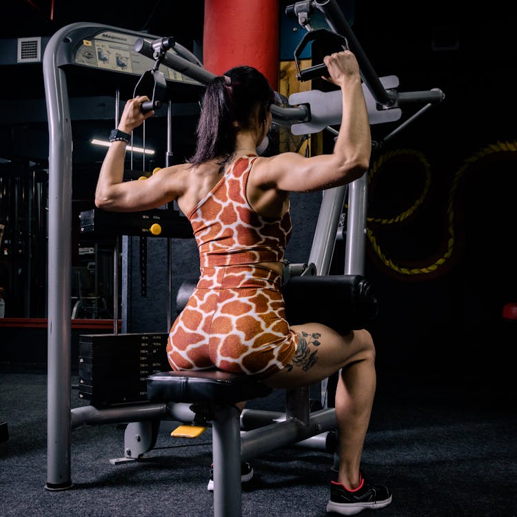 A Woman In Brown Leopard Print Clothes Sitting On Black And Gray Exercise Equipment