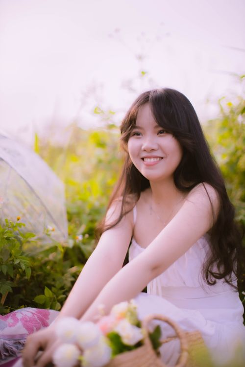 Free Charming outdoor portrait of a smiling woman in natural light, surrounded by greenery. Stock Photo
