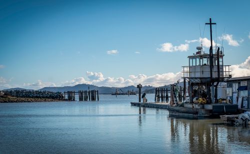 Free Peaceful harbor view featuring a dock, mountain backdrop, and blue sky. Stock Photo